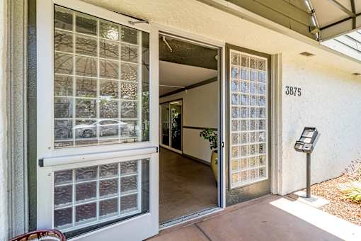A glass door with a metal frame is open to a hallway.