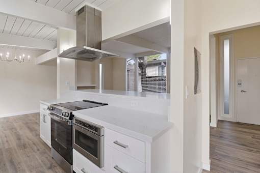 A modern kitchen with a stainless steel range hood and double ovens.