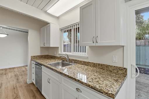 A kitchen with granite countertops and white cabinets.