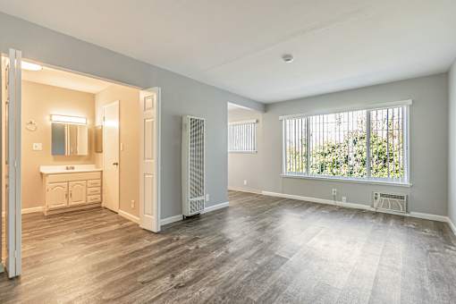 A large empty room with a window overlooking trees.