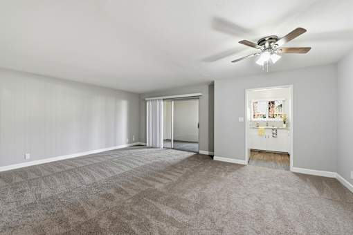 A room with a ceiling fan and carpeted floor.