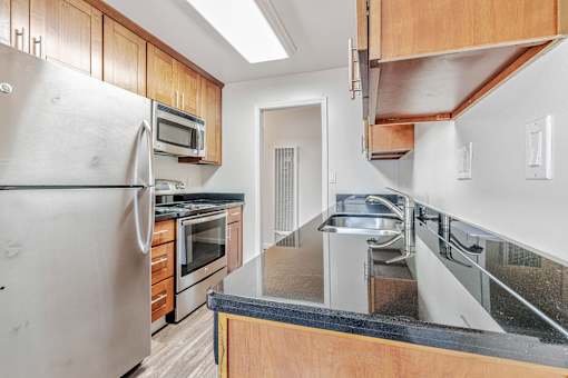 A kitchen with a stainless steel refrigerator and wooden cabinets.