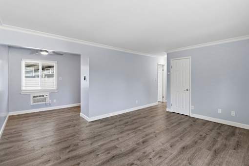 A room with wooden flooring and a window with blinds.