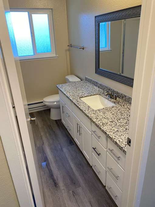 A bathroom with a granite counter top and white cabinets.