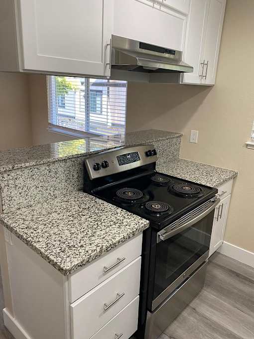 A kitchen with granite countertops and white cabinets.