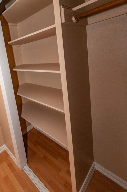 a closet with white shelves and a door