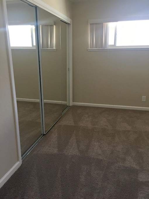 a room with a carpeted floor and a mirrored closet