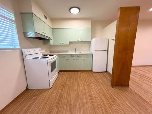 A kitchen with a white stove and green cabinets.