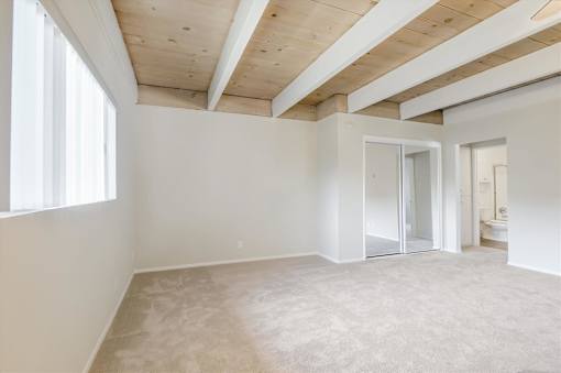 A spacious room with a wooden ceiling and carpeted floor.