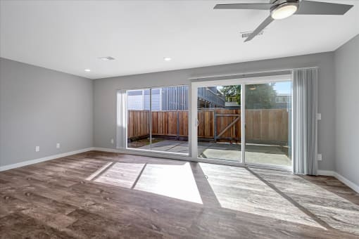 an empty living room with sliding glass doors to a patio