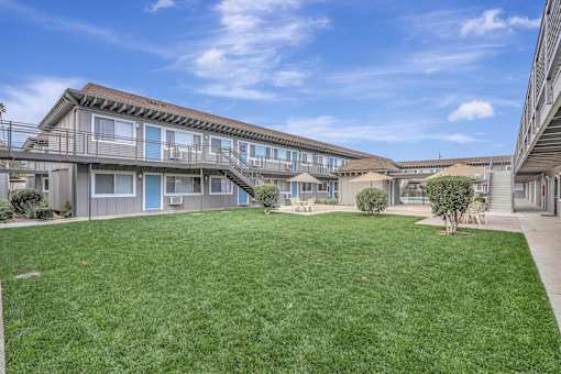 the backyard of a condo building with green grass and a lawn