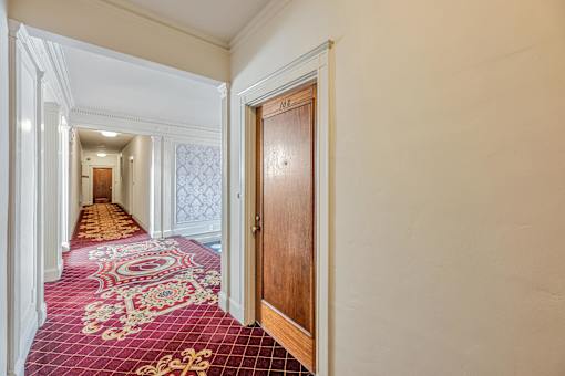 A hallway with a red carpet and a wooden door.