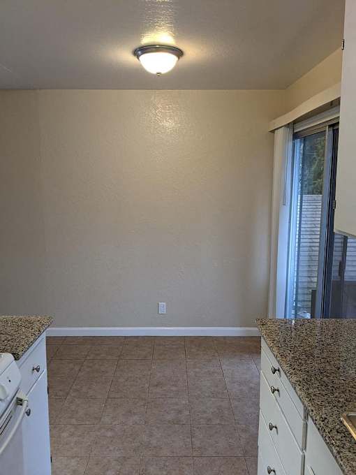 A kitchen with granite countertops and white cabinets.