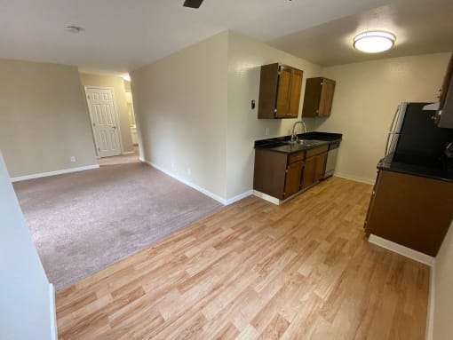 an empty kitchen and living room with wood flooring and