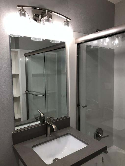 A bathroom with a sink, mirror, and shower.