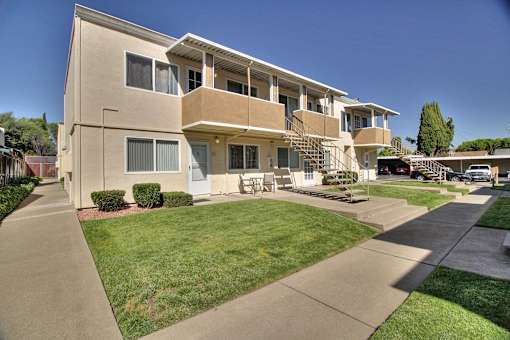 A beige apartment building with a green lawn in front.