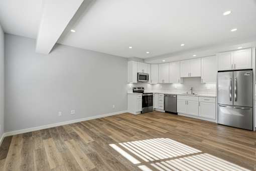A kitchen with white cabinets and a wooden floor.