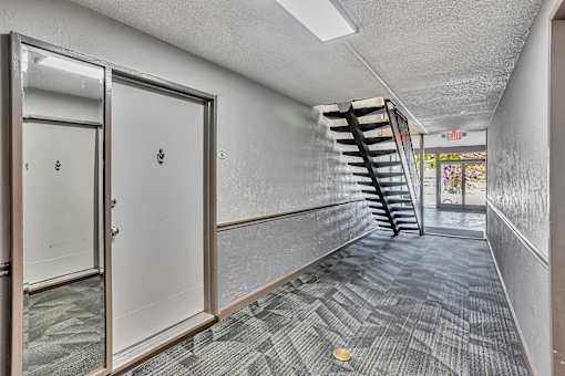 A hallway with a staircase on the right and a door on the left.