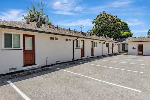 A row of houses with a parking lot in front.
