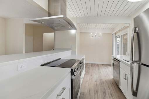 A modern kitchen with stainless steel appliances and wooden floors.