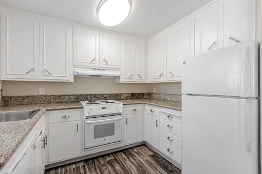 A white kitchen with a refrigerator on the right.