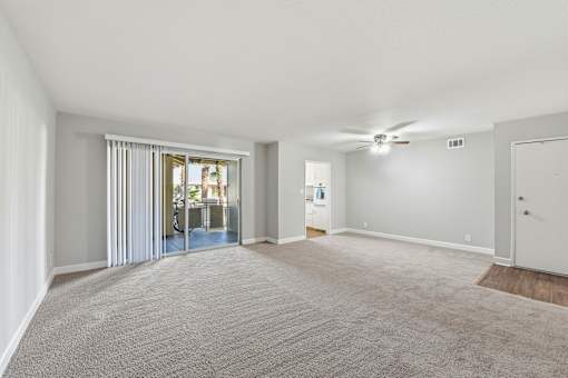 A spacious room with a carpeted floor and a ceiling fan.