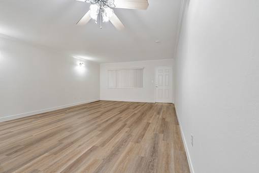 A room with a ceiling fan and wooden flooring.
