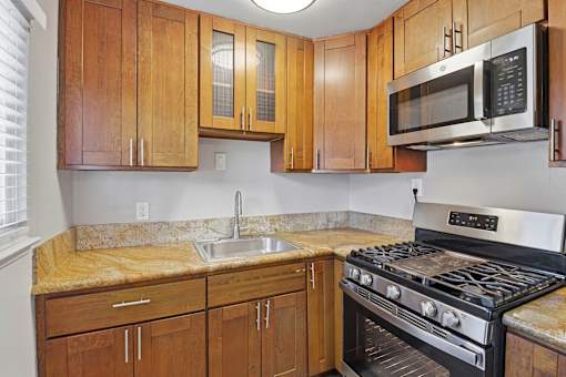 A kitchen with a stove, sink, and cabinets.