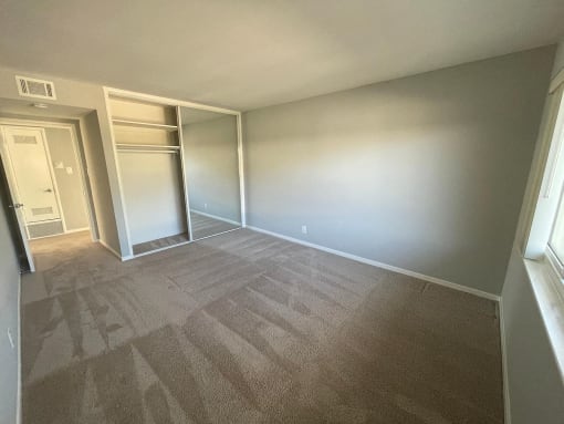 an empty room with a closet and a window