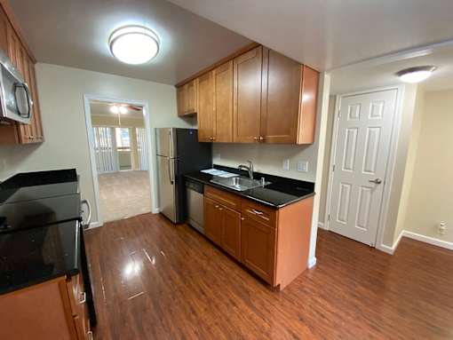 A kitchen with wooden cabinets and black countertops.