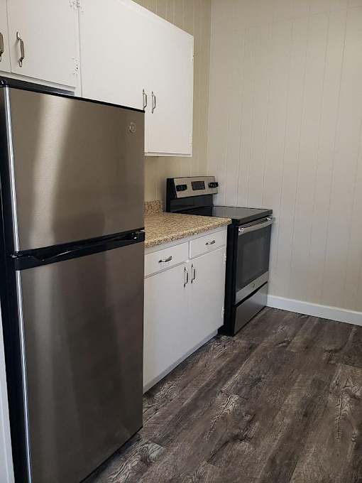 A kitchen with a stainless steel refrigerator and white cabinets.