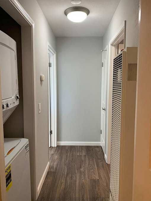 A long hallway with a washer and dryer on the left and a heater on the right.