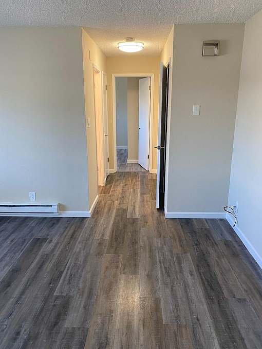 A hallway with wood flooring and white walls.