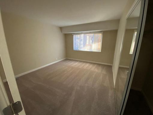 A room with a window and a carpeted floor.