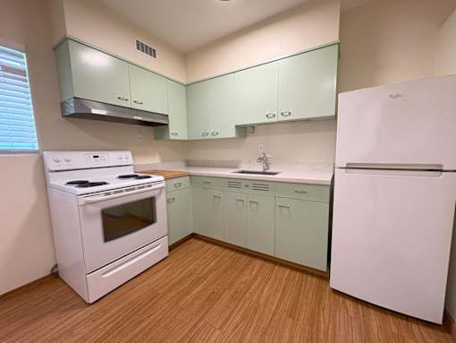 A kitchen with white appliances and green cabinets.