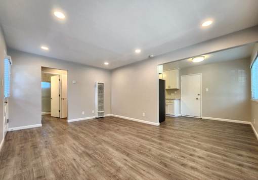 A spacious room with wooden flooring and white walls.