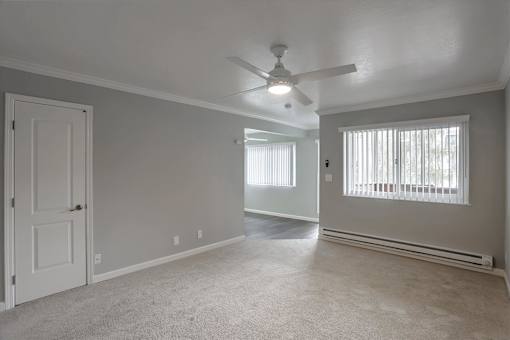A room with a ceiling fan and a window with blinds.