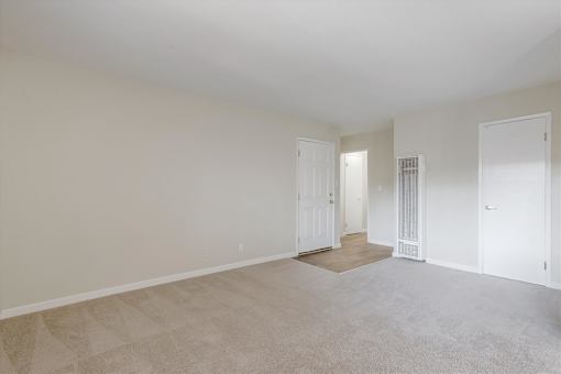 A large, empty room with carpeted flooring and white walls.