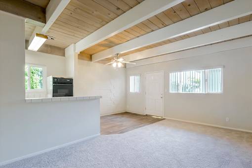 A spacious room with a wooden ceiling and a flat-screen TV mounted on the wall.