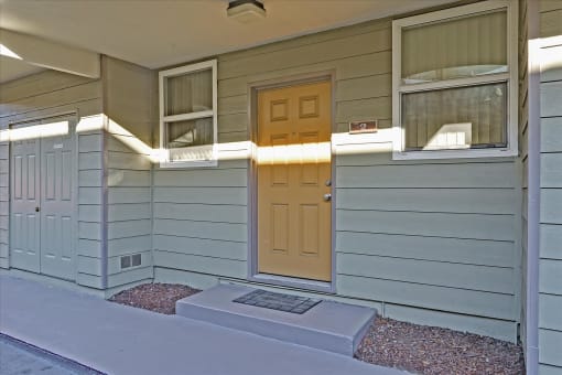 A small house with a brown door and a small porch.