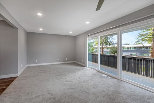 an empty living room with large windows and a balcony