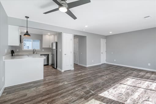 a living room with a kitchen and a ceiling fan