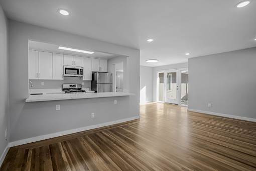 A kitchen with white cabinets and a wooden floor.