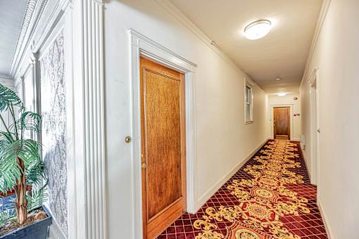 A long hallway with a red carpet and white walls.