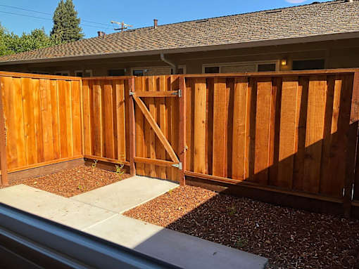 A wooden fence with a gate is in front of a house.