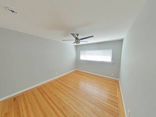 A room with a ceiling fan and wooden flooring.
