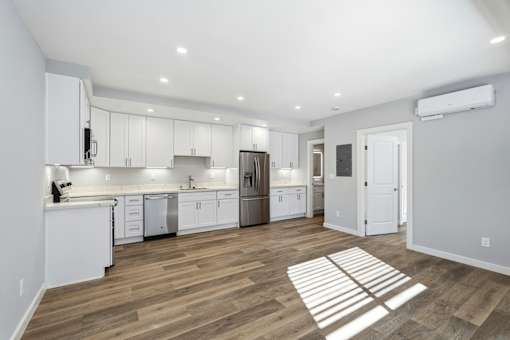 A kitchen with white cabinets and a wooden floor.