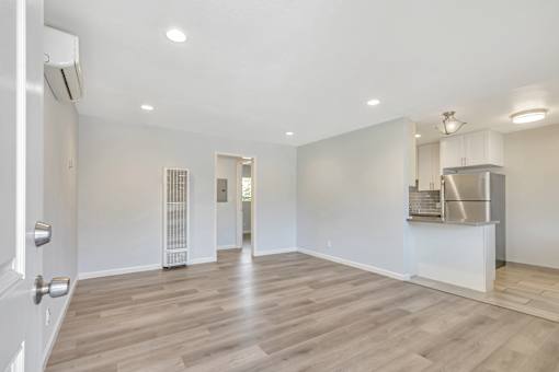 A spacious room with wooden flooring and white walls.