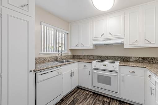 A white kitchen with a sink, stove, and oven.