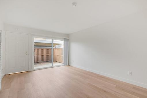 A room with a white door and wooden flooring.